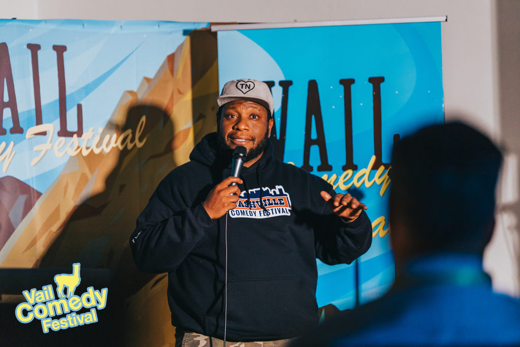 2023 Vail Comedy Festival - Brad Sativa reps his home state of Tennessee with hoodie and hat while on stage during a showcase